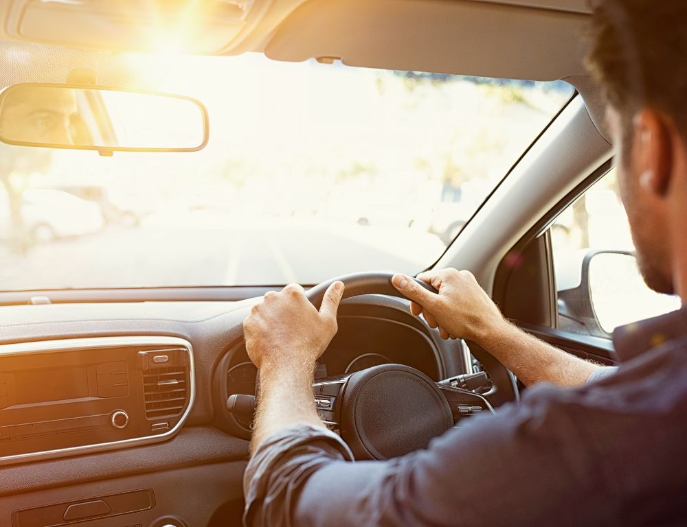 homme qui conduit face au soleil